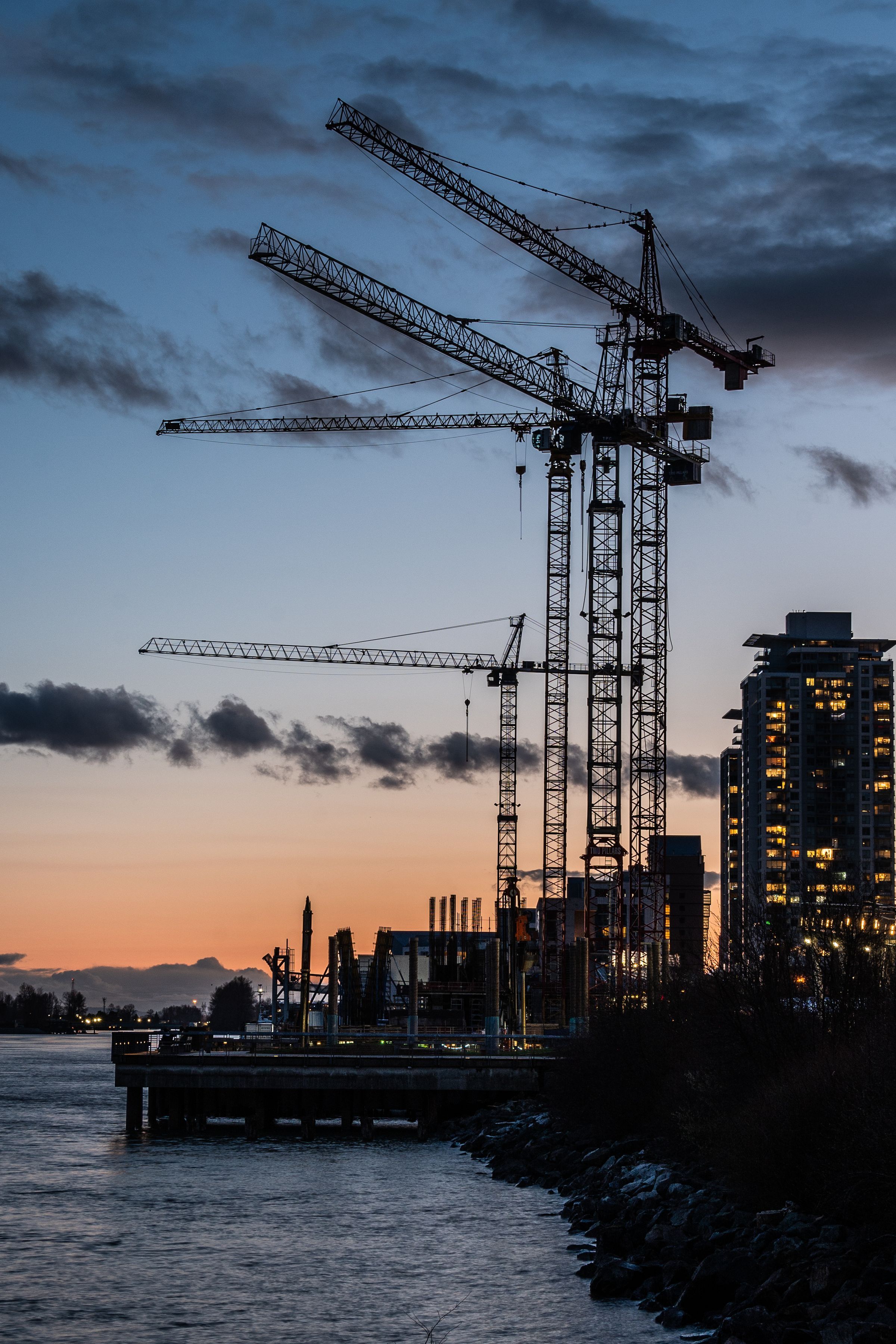 Tower cranes in silhouette against a dusk sky