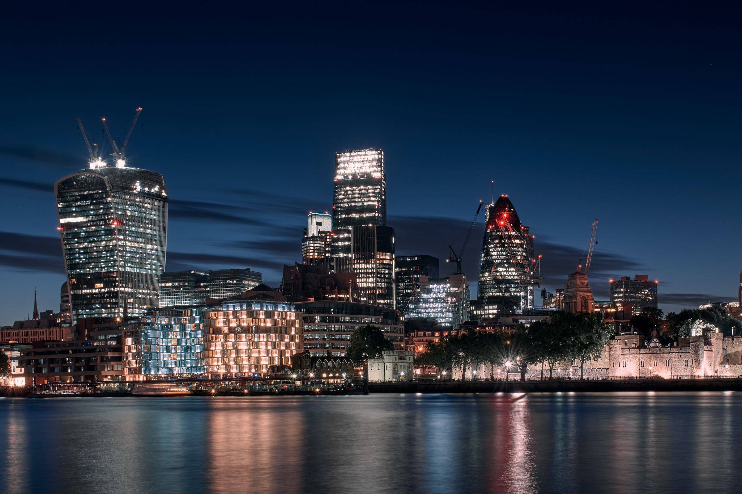 The City of London skyline at night, reflected in the Thames