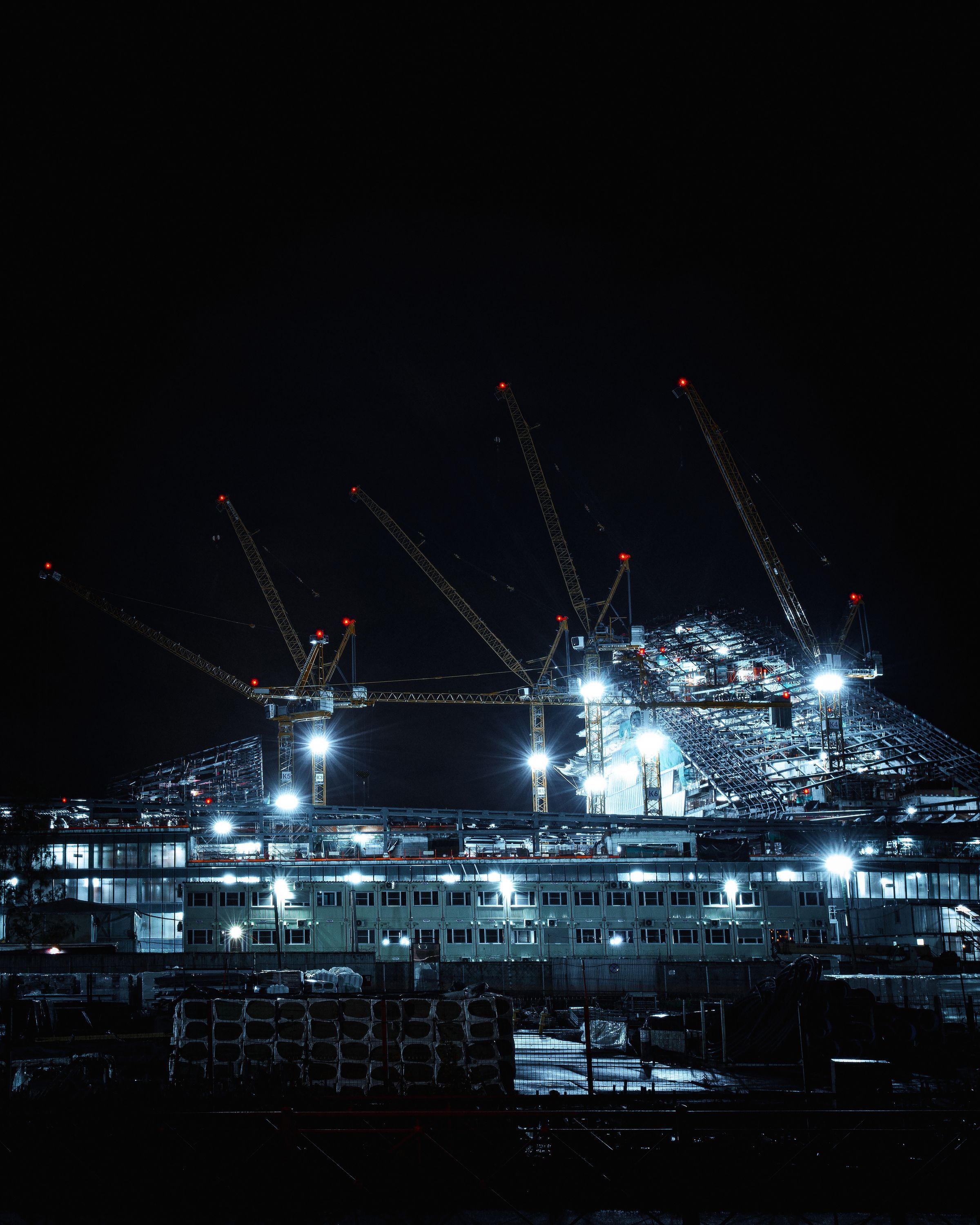 A construction site lit at night with tower cranes