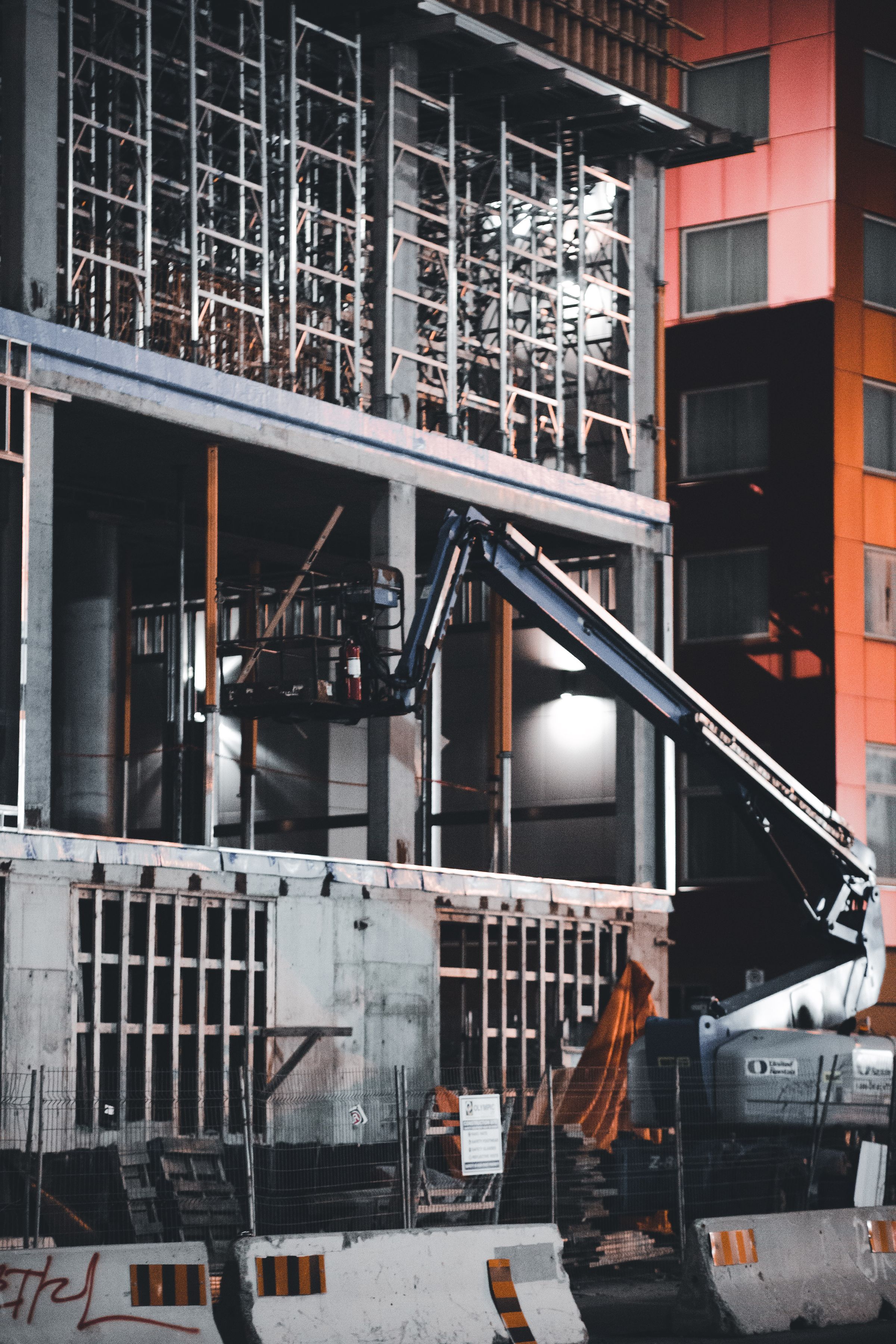 The steel frame of a building under construction, lit at night
